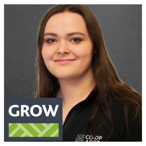 A smiling female Co-op employee, with shoulder length brown hair, wears a black shirt with the Co-op Agro logo on the right chest. The Co-op Grow Team logo is presented at the bottom with the word "Grow" and a two-tone geometric pattern.