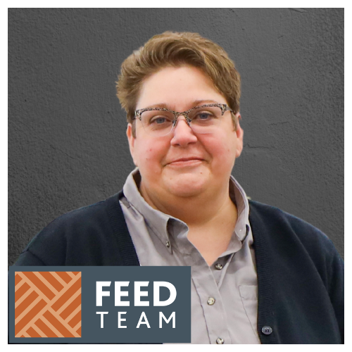 A smiling female Co-op employee is wearing a grey button up shirt, with a black sweater. Her hair is short and she is wearing glasses. The words "Feed Team" appear in a grey box, with a brown and beige geometric pattern beside.